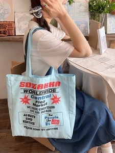 Light blue canvas tote bag with retro typography shown in a cozy lifestyle setting