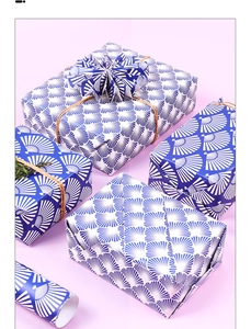 Deep blue fan-patterned gift wrap paper roll and wrapped boxes on soft purple background