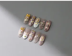 Detail of grey handmade press-on nails with 3D golden bows, pearls and plaid pattern