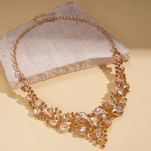 Detail of luxury teardrop champagne diamond necklace and gold chain on stone pedestal