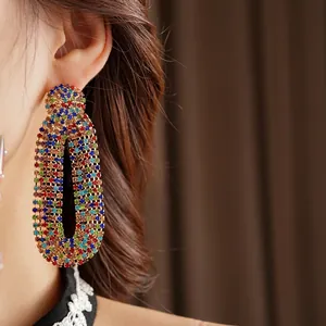 Vintage gold oval drop earrings with colorful zircon stones worn by a model