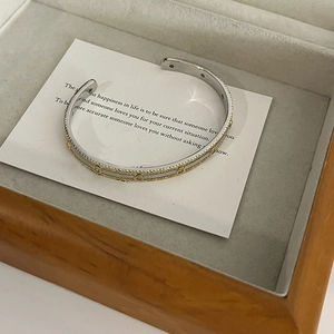 Detail of 18K gold plated two-tone open bangle with cubic zirconia in a jewelry box