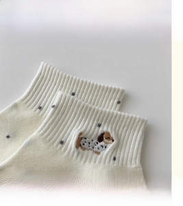 Detail view of cream cotton socks featuring grey polka dots and puppy embroidery