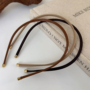 Close-up of thin leather headbands in earth tones with refined gold metal end tips