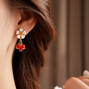 Detail shot of vintage earrings with white flower and red pomegranate fruit charms