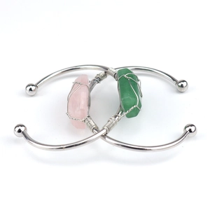 Detail of silver wire-wrapped natural crystal open bracelets in pink and green colors