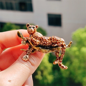 Elegant gold-tone leopard brooch with brown enamel spots held in natural light