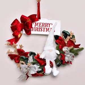 Christmas wreath with gnome, red velvet bow and Merry Christmas sign on white wooden door