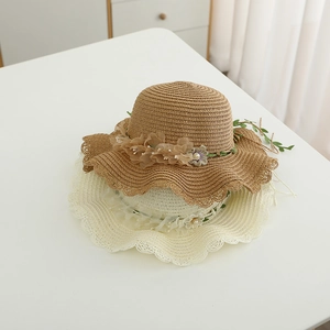Detail of woven straw hats featuring chiffon flowers, pearls and wavy lace edges