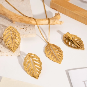 Vue à plat d'un ensemble de bijoux en feuilles évidées dorées avec collier et boucles