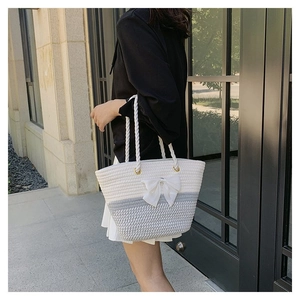 Detail of grey and white woven tote bag featuring a large bow and rope handles