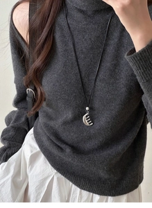 Close-up of a silver comb pendant necklace worn on a textured dark grey knit sweater