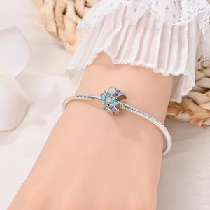 Detailed view of silver charm bracelet featuring blue lotus bead with purple crystals