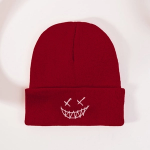 Detailed view of dark red knit beanie featuring white embroidered ghost face pattern