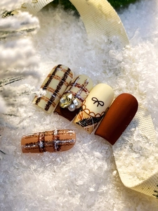 Macro view of vintage brown plaid nail stickers with pearls and diamond accents