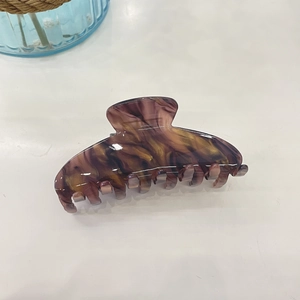 Detailed macro view of large acetate hair claw clip with purple and gold marble texture