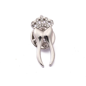 Detailed view of silver tooth-shaped brooch featuring a sparkling crystal crown design
