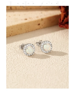 Detail view of round synthetic opal stud earrings with zircon halo on stone base