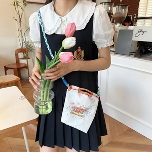 Mini white canvas crossbody bag featuring colorful embroidery and woven rope strap
