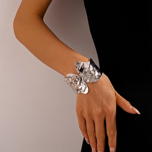 Detailed close-up of a silver irregular hammer-textured open cuff bracelet on a female wrist