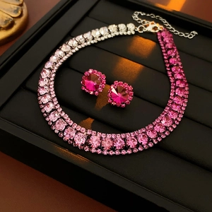 Macro shot of gradient pink diamond necklace and earrings on black display tray