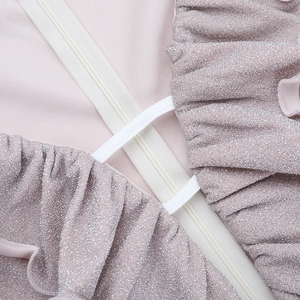 Detail of pink sequin fabric with silver glitter and white zipper closure