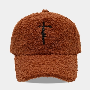 Detailed view of caramel brown sherpa baseball cap with black cross embroidery