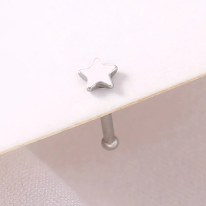 Macro shot of silver stainless steel star-shaped nose stud piercing on white background