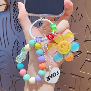 Rainbow beaded keychain with smiley sunflower and heart pendant held in hand