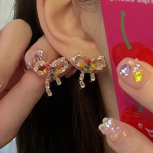 Detail of elegant bow stud earrings with colorful zircon stones on person ear