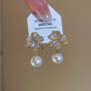 Macro shot of S925 silver flower earrings with zircon petals and round white pearl drops