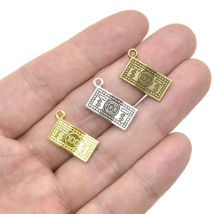 Tres colgantes metálicos con forma de billete de 100 dólares en oro, plata y bronce