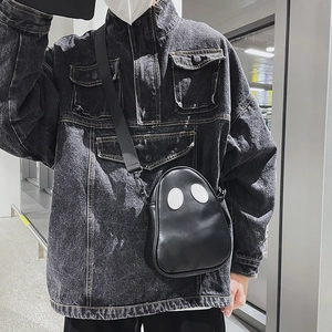 Detail of creative ghost crossbody bag with white eyes on black faux leather material