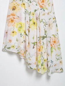Detail of floral chiffon skirt featuring yellow print and asymmetric hem on white base