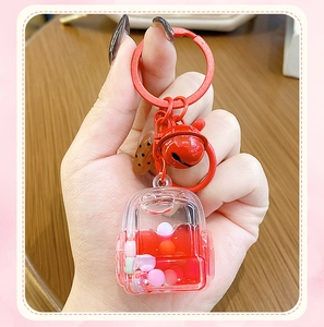 Detail shot of a red schoolbag keychain featuring flowing liquid quicksand and a bell