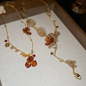 Detail of amber acrylic flower pendants with chiffon petals on vintage gold necklaces