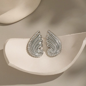 Detailed view of silver wing-shaped stud earrings with sparkling rhinestones on ceramic