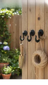 Ganchos de pared vintage de hierro negro instalados en un poste de madera de jardín