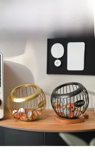 Detail view of spherical wire coffee pod holder in matte black and gold finish