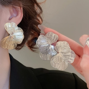 Détail de grande boucle d'oreille fleurie ajourée avec pétales en métal brossé pour femme