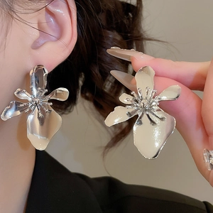 Close-up of oversized silver flower earrings with metallic finish on model