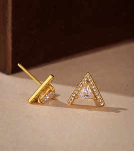 Macro shot of V-shaped triangle stud earrings with gold plating and clear zircons