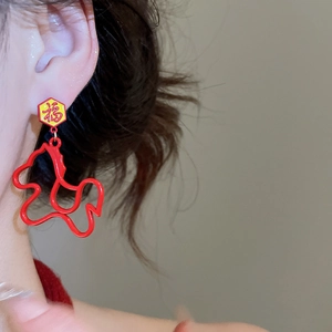 Detail view of red and gold Fu character earring with hollow horse pendant on model