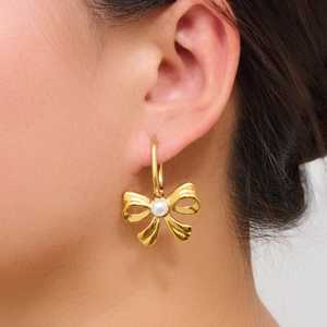 Elegant 18K gold plated bow earrings with white pearls worn by a female model