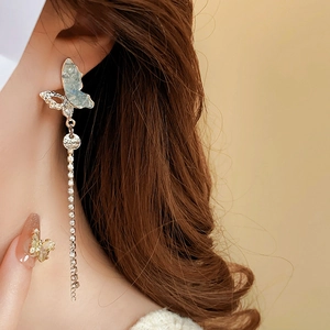 Close-up of golden butterfly fringe earrings with rhinestones and blue textured wings