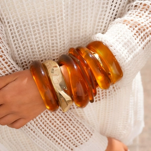 Nahaufnahme von Retro-Bernstein-Resin-Armreifen kombiniert mit einem goldenen Armband