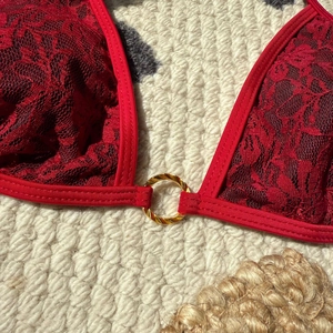 Red lace bikini top with floral patterns and a gold metal ring detail on the center