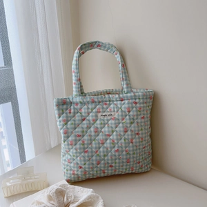 Detailed close-up of blue gingham quilted handbag with tulip and bow patterns
