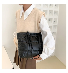 Quilted black puffer tote bag with long handles shown on model in a modern minimal studio