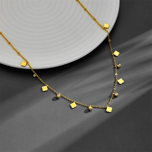 Close-up of golden stainless steel necklace with clover charms and cubic zirconia details